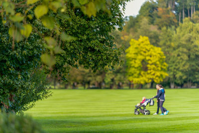 Full length of man and woman with baby stroller on golf course