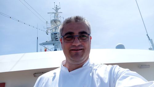 Close-up portrait of mature man traveling in boat against sky during sunny day
