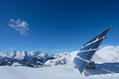 Solar panel on snow covered ground against sky