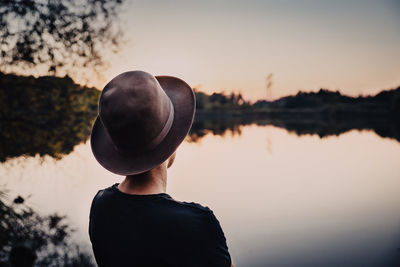 Rear view of man looking at lake against sky