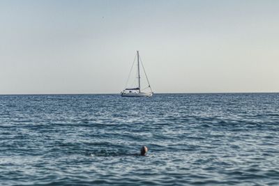 Sailboat sailing in sea against clear sky