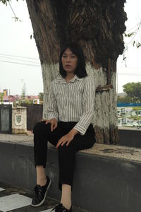 Portrait of teenage girl sitting against tree