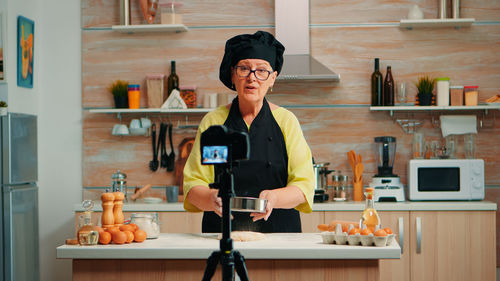 Portrait of young woman standing in kitchen