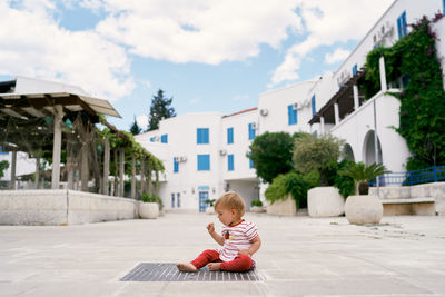 Full length of cute boy sitting against sky