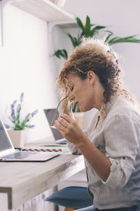 Side view of woman using mobile phone while sitting on table