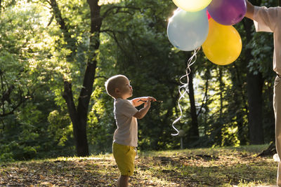 Little boy plays with balloons in the park.