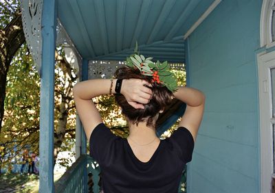 Midsection of woman with arms raised standing against wall