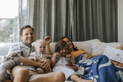 Happy family enjoying with each other while sitting on sofa at home