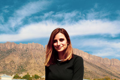 Portrait of smiling young woman against sky