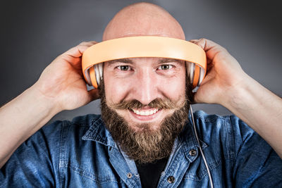 Portrait of man holding headphones against gray background