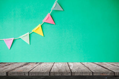 Close-up of wooden table against colorful bunting flag on wall