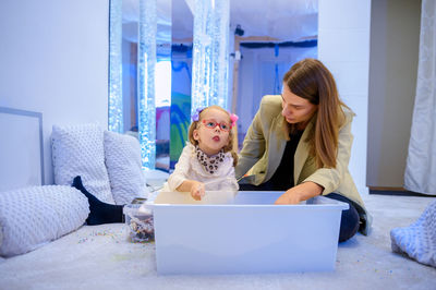 Child living with cerebral palsy interacting with her therapist during therapy session.