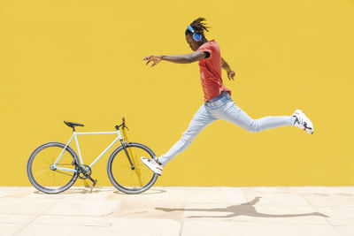 Black male leaping near bicycle