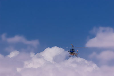 Low angle view of helicopter flying against blue sky
