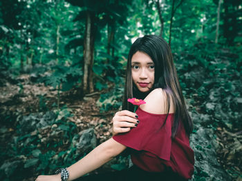 Portrait of beautiful young woman standing against plants