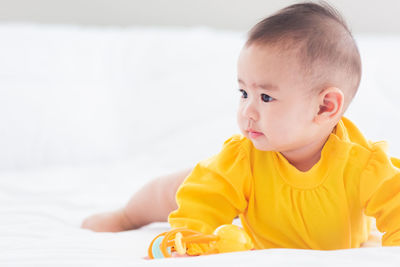 Close-up of cute baby girl lying on bed