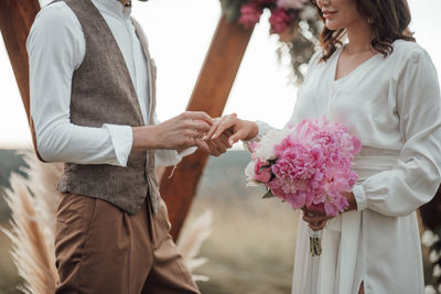 Midsection of couple holding flower bouquet