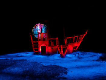 Illuminated ferris wheel at night during winter