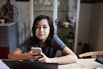 Portrait of smiling boy using mobile phone for homework at home