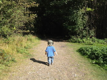 Full length rear view of boy walking on footpath