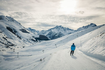 Rear view of man on snowcapped mountain against sky