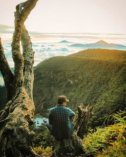 Rear view of man looking at mountains against sky