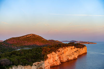 Rocks by sea against sky during sunset