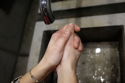 Cropped image of woman washing hands in sink at home