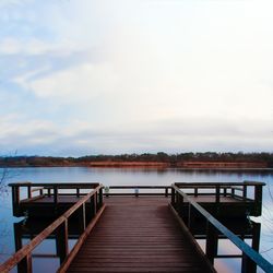 Empty pier over lake against sky