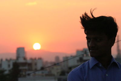 Portrait of young man looking away against sky during sunset