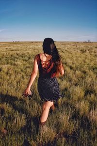 Rear view of woman on field against sky