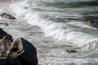 High angle view of waves splashing on rocks