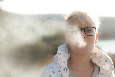 Close-up portrait of woman wearing eyeglasses smoking