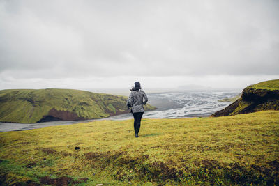 Rear view of woman standing on top of green mountain