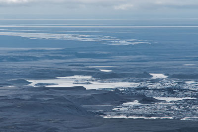Aerial view of snowcapped mountain by sea against sky
