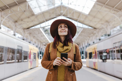 Young woman using mobile phone at railroad station