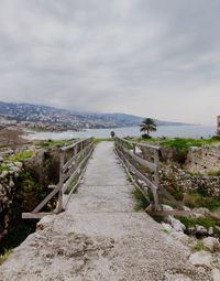 Footpath leading towards sea landscape against sky