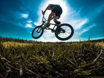 Low angle view of man riding bicycle on field
