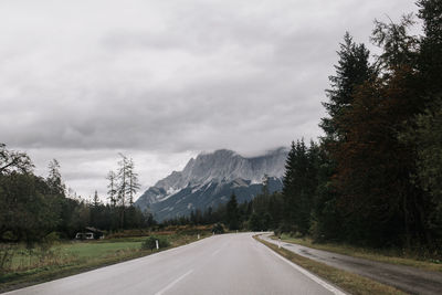 Road by trees against sky