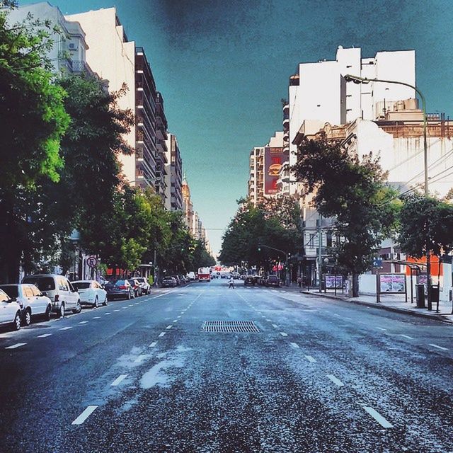 building exterior, architecture, built structure, street, city, road, transportation, the way forward, road marking, car, tree, incidental people, city street, building, city life, sky, asphalt, diminishing perspective, day, sunlight