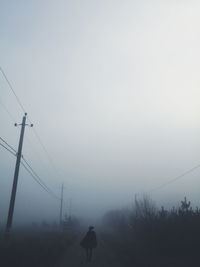 Silhouette of electricity pylon on land against sky