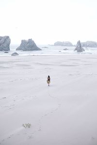 Mid distance of woman walking on sand against sea at beach