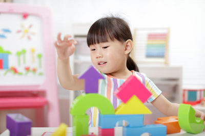Young girl playing toy blocks at home 