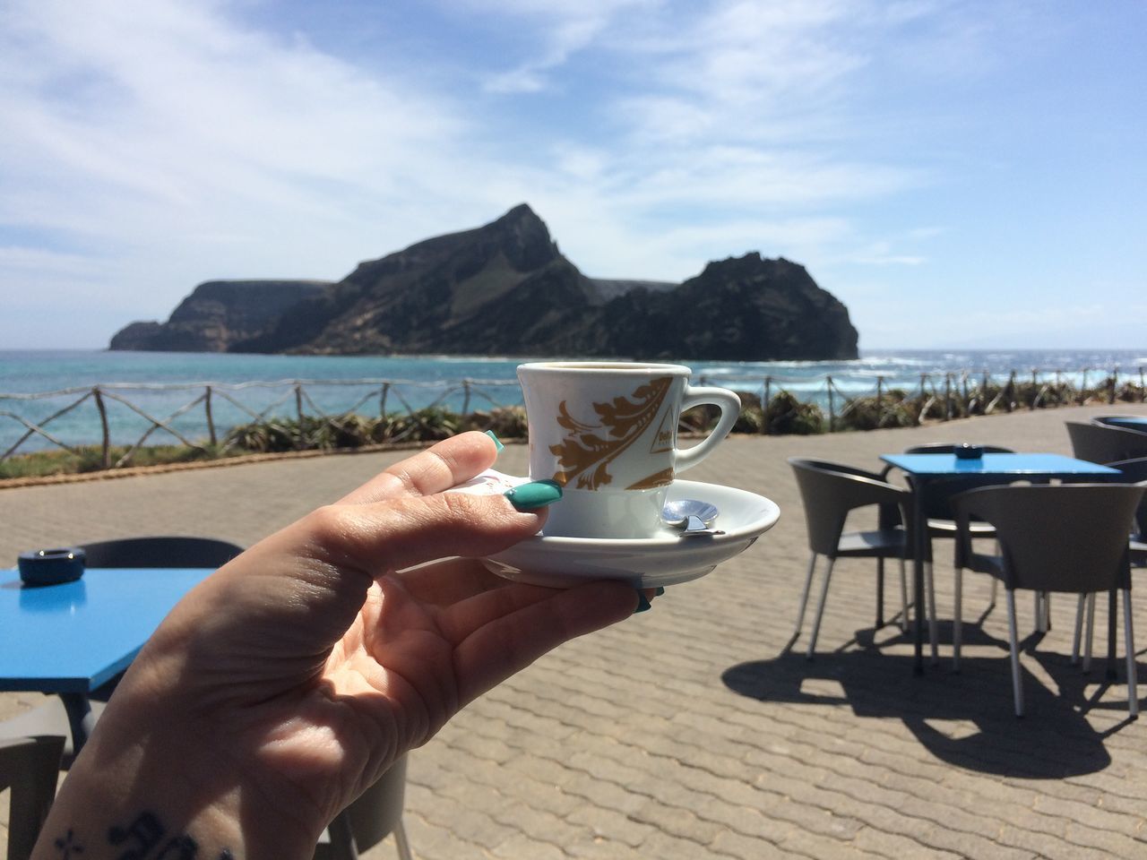 lifestyles, leisure activity, sea, water, holding, personal perspective, sky, person, food and drink, drink, part of, table, sitting, cropped, refreshment, mountain, men