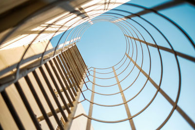 Low angle view of metal fence against blue sky