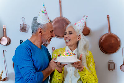 Senior couple holding birthday cake standing in kitchen