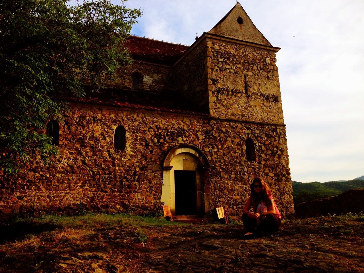 architecture, built structure, building exterior, sky, history, old, arch, grass, abandoned, old ruin, tree, the past, house, cloud - sky, low angle view, stone wall, day, field, outdoors, castle