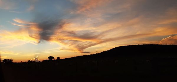 Silhouette landscape against dramatic sky during sunset