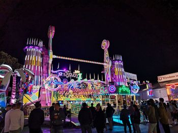 People at amusement park against sky at night