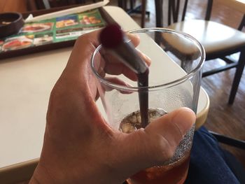 Cropped image of person holding ice tea in glass at restaurant
